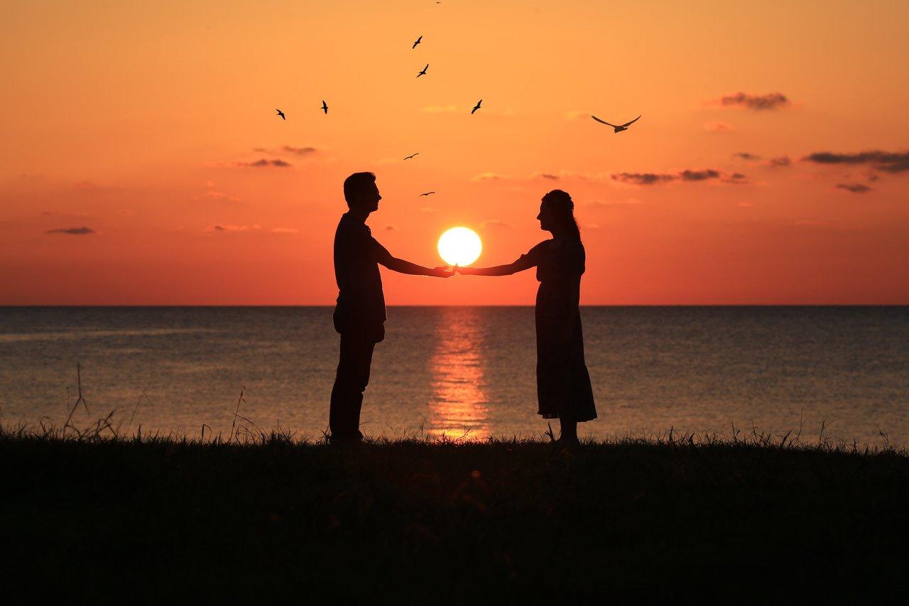 Couple admirant le panorama romantique des falaises d’Étretat au coucher du soleil, un moment inoubliable.