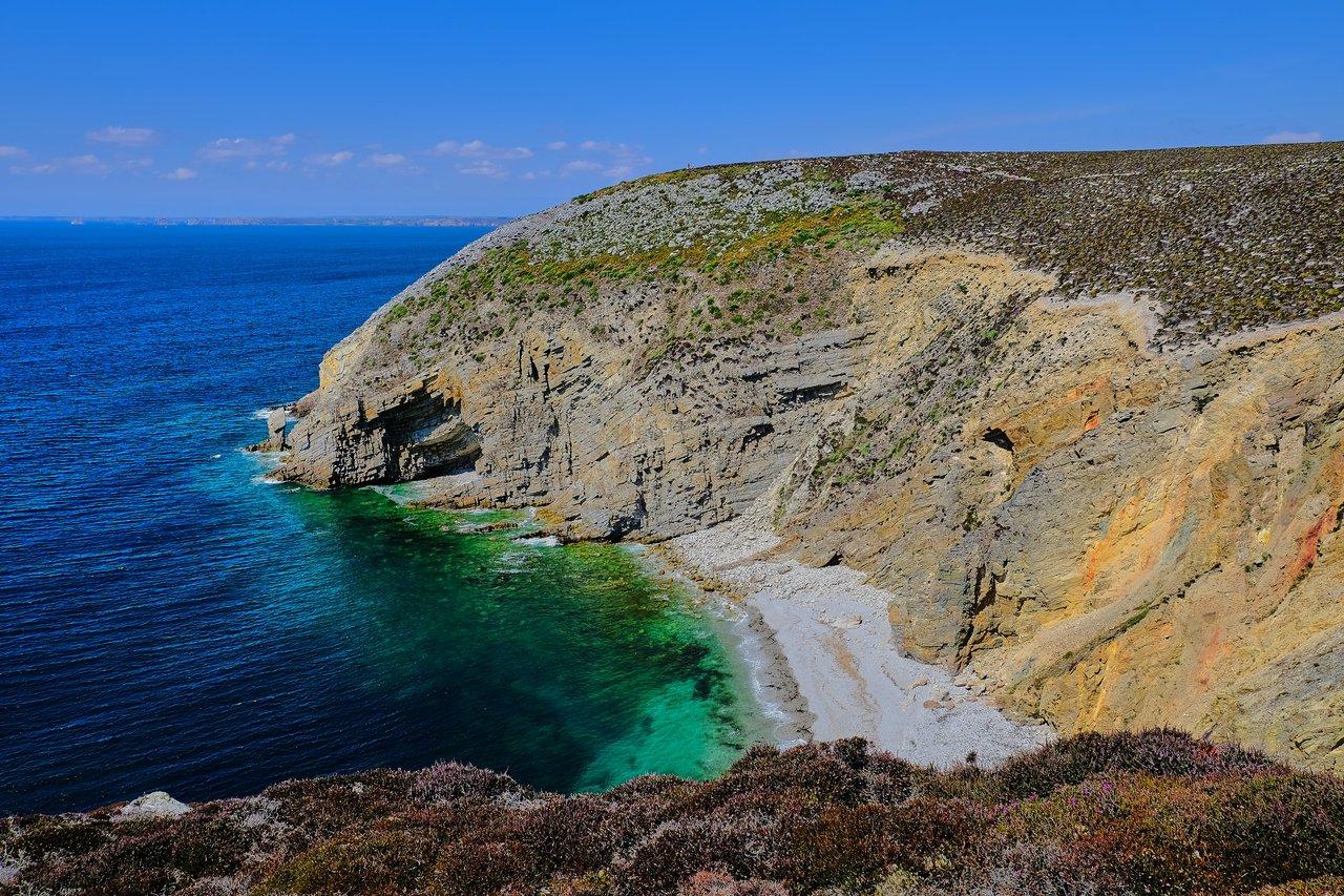 Panorama des falaises du Cotentin, vue spectaculaire sur la Manche avec brume légère et végétation côtière.