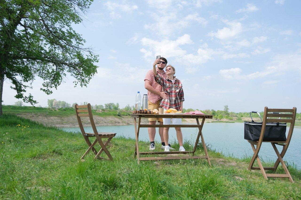Un couple profite d’un picnic lakeside paisible au camping Le Lac des Charmilles en Normandie.