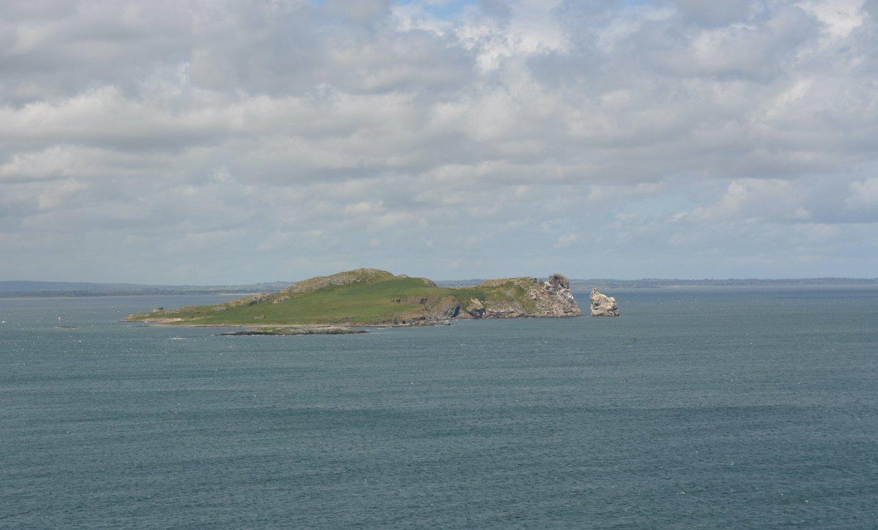 Vue panoramique des îles Chausey avec eaux turquoise, îlots granitiques et bateaux de pêche traditionnels.